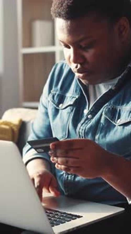 Young Adult Types on Laptop Holding Credit Card
