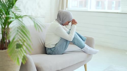 Woman Sitting Curled up on Sofa, Looking Sad