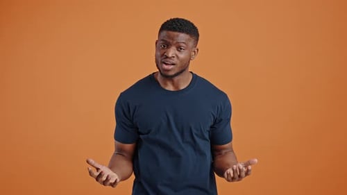 Confused Darkskinned Guy Asking What Looking Astonished at Camera Isolated on Orange Background