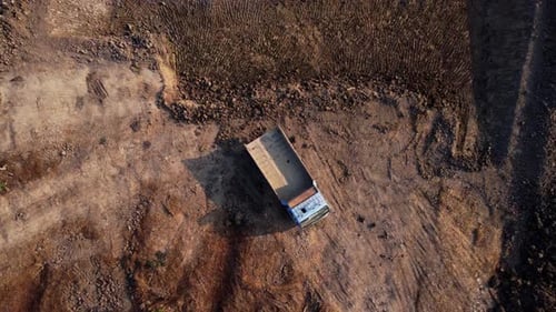 Aerial view of a wheel loader excavator with a backhoe loading sand into a heavy earthmover