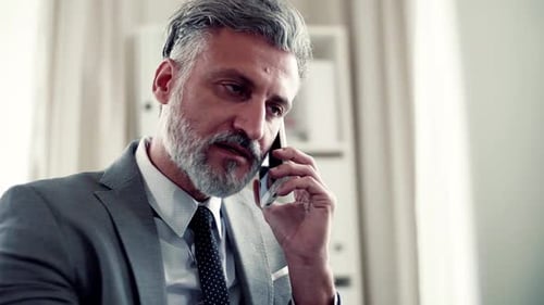 Serious Mature Businessman with Smartphone Making a Phone Call