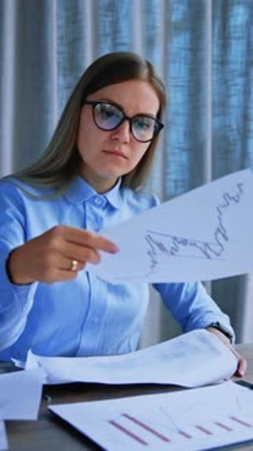 Busy annoyed business lady sitting at desk looking through the papers throwing them away.