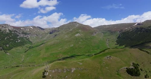 Beauty of tall mountain ranges covered in lush green forests and grass, captured from above on a sun