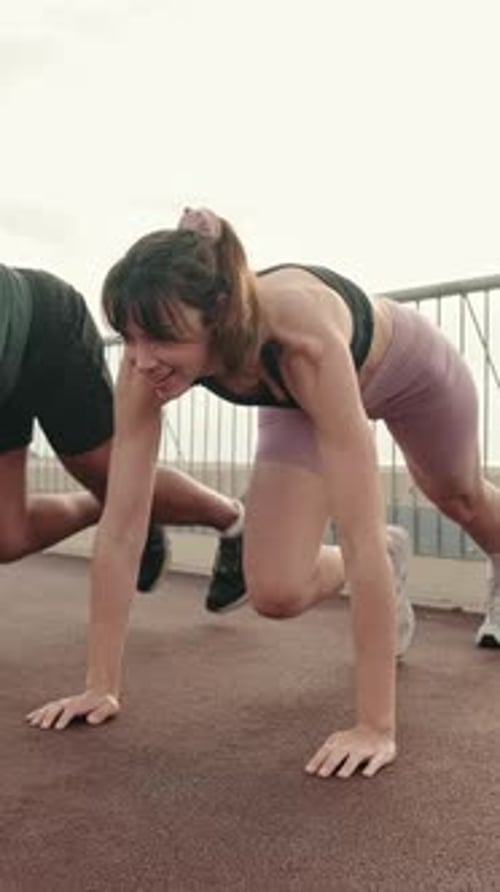Woman and Man Doing Mountain Climbers on Rooftop