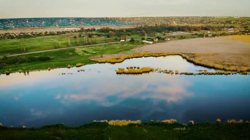 Luftaufnahme der wunderschönen Naturlandschaft der Kleinstadt neben dem Fluss und der Großstadt in der Ferne