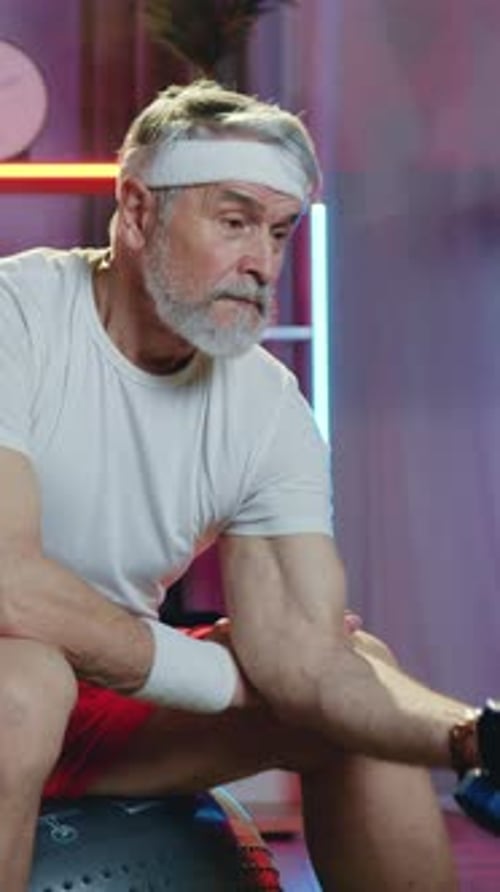 Senior Man Lifts Weights on Exercise Ball at Home