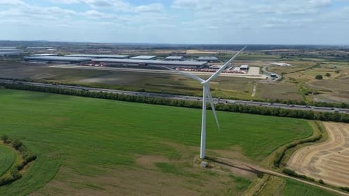 Aerial drone view of wind turbine renewable energy power generation with motorway traffic and