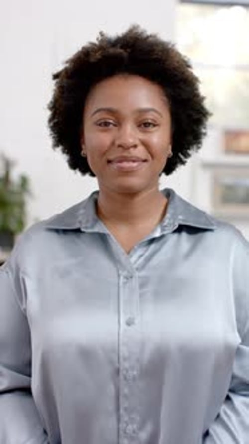Vertical video of portrait of happy african american casual businesswoman in office, slow motion