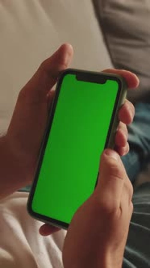Close-up of the hands of man lying on sofa using mobile phone