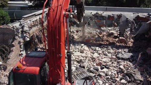 Aerial orbiting shot of a crane demolishing the remains of a building