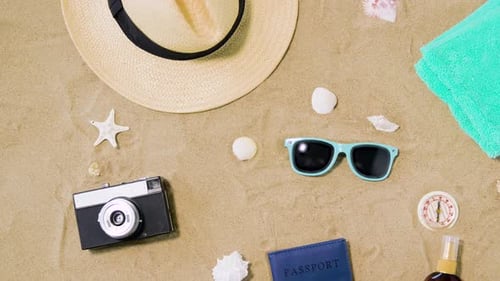 Vintage camera passport and sunglasses laying on beach sand for a summer vacation