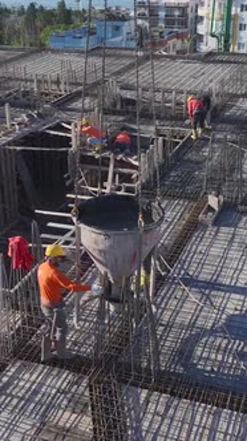 Vídeo vertical de una nueva casa en construcción con constructores instalando soportes metálicos y tendiéndolos