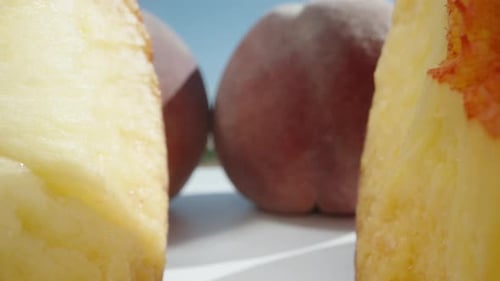 Pfirsiche auf einem weißen Tisch unter Sonne und blauem Himmel, ein in zwei Hälften geschnittener Pfirsich, ein Stein. Dolly Slider extra