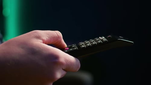 Close Up of Man on Couch Using Remote Control Flipping Through Channels on TV