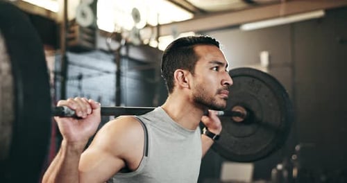 Man at gym, weight lifting and barbell with focus on muscle building endurance