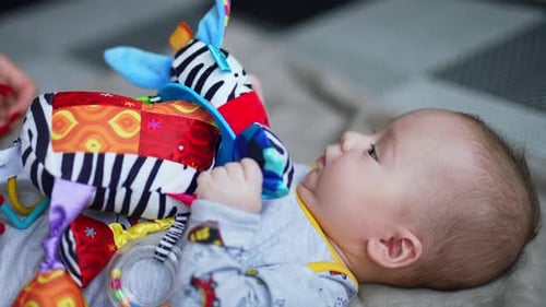 Schönes Kind schnappte sich ein buntes Spielzeugtier. Mutter spielt mit ihrem kleinen Sohn. Nahaufnahme.