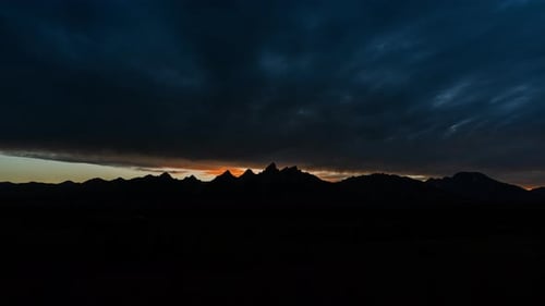 La lumière du jour s'estompe au-dessus des montagnes, les nuages en mouvement pleins de couleurs du coucher de soleil s'assombrissent