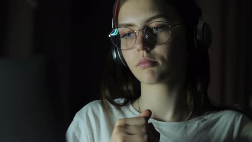 Teenage Girl with Glasses Looks at the Monitor Plays a Game Reads Studies Late at Night