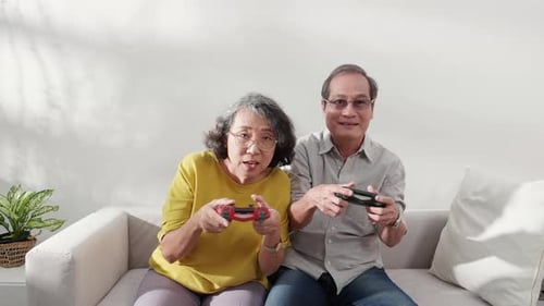 Senior Couple Enjoy Playing Video Games Together at Home