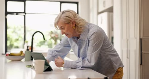 Senior Woman Using Tablet Device in Bright Kitchen
