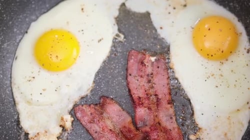 Crispy Bacon and Eggs Cooking in a Pan
