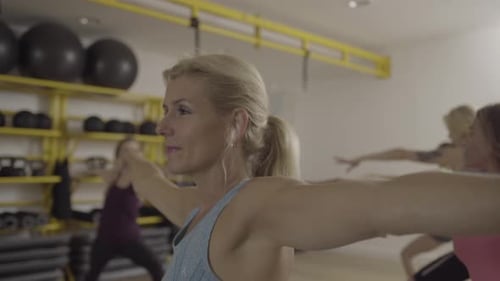 Group of adult women doing yoga exercises in gym