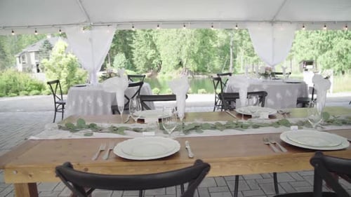 Elegant banquet tables for outdoor wedding. Decoration with leaves and nature. Panning.
