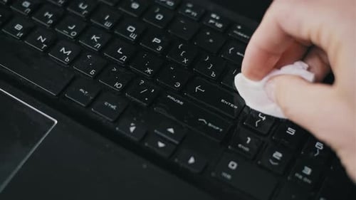 Cleaning a Black Laptop Keyboard with Disinfectant