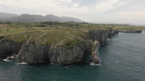 Birds Eye View of a Cliff with a Green Hillside Above It in Northern Spain