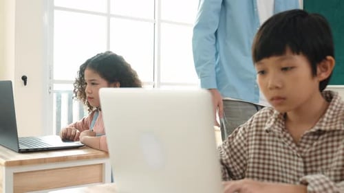 Caucasian teacher helping asian student coding engineering prompt. Pedagogy.