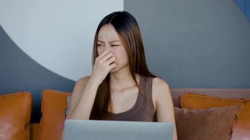 Während eine junge Frau auf einem bequemen Sofa in ihre Arbeit vertieft ist, stößt sie plötzlich auf einen üblen Geruch