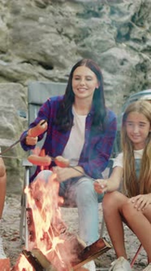 Happy Smiling Mother Father with Two Children Cooking Sausages on Bonfire at Forest Camp Near