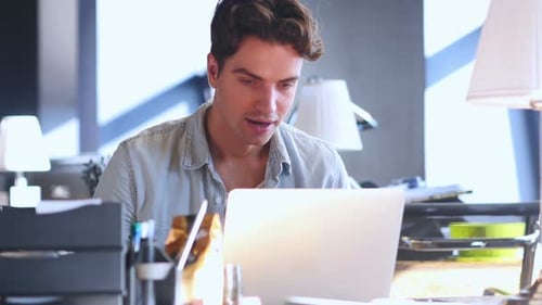 Man Celebrates Success Working on Laptop at Home