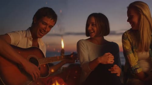 Friends Play Guitar by Bonfire on the Beach