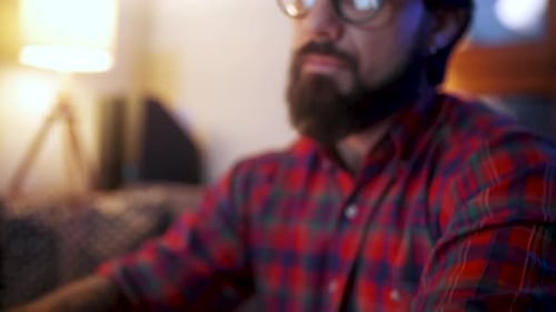 Focused Bearded Professional Working on Laptop at Night Hand Holding Smartphone with Green Screen