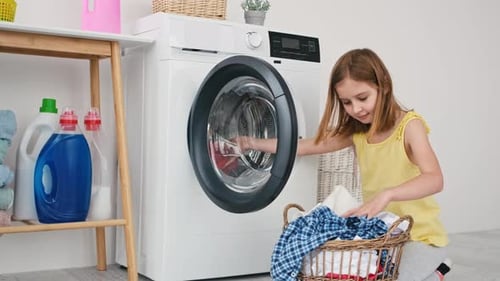 Kleines Mädchen lädt Kleidung in die Waschmaschine