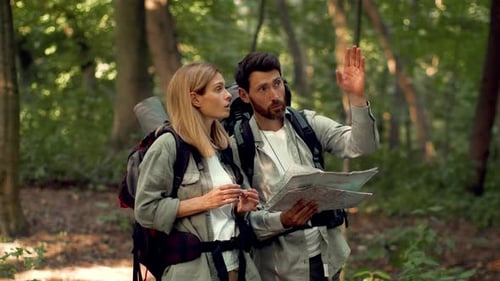 Couple with Backpacks Looking at Map in Forest