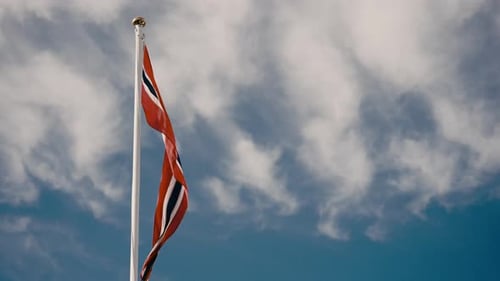 Bright Red Flag Waving Against Cloudy Blue Sky