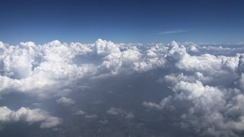 Aerial view of fluffy white cumulus clouds from above with clear blue sky background