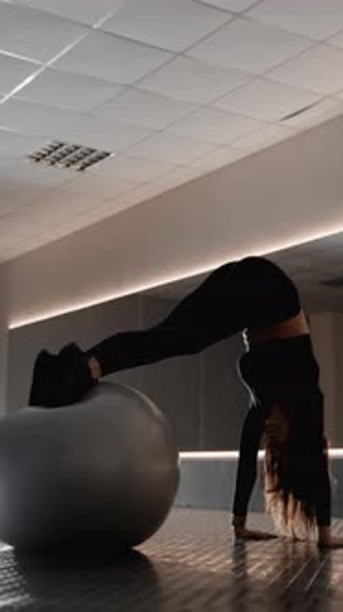 Athletic Woman Balances in Gym with Exercise Ball