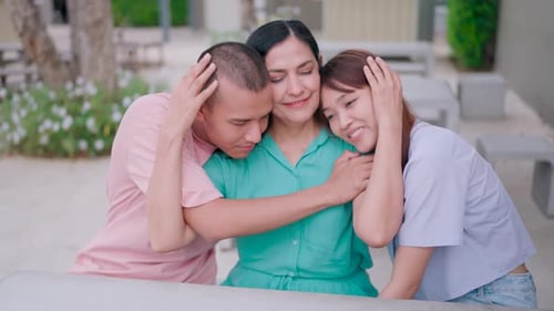 Close-up of two children hugging their mother with love and care. Looking at the camera smiling as a