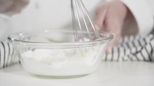 Person Mixing Ingredients in a Glass Bowl