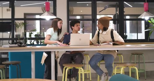 African American students, woman approaching laptop at lounge working together pointing high-fiving