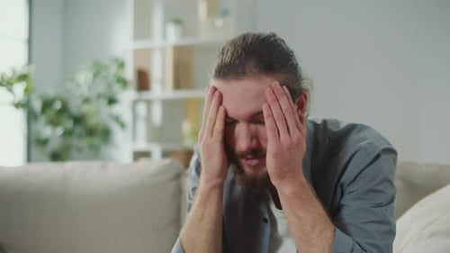 Un homme bouleversé souffrant de maux de tête essaie de se détendre et de soulager la douleur en lui massant la tête