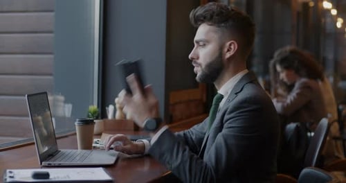 Adult Man Working on Laptop and Talking on Phone