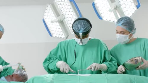 Diverse surgeons wearing surgical gowns operating on patient in operating theatre, slow motion