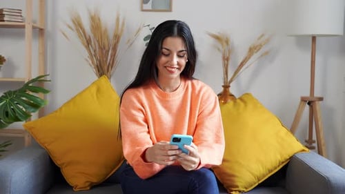Woman Relaxing on Couch Using Smartphone