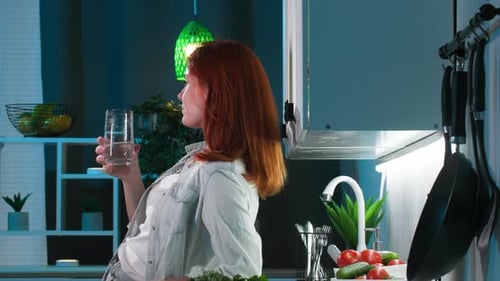 Woman Drinks Water in Clean Kitchen at Night