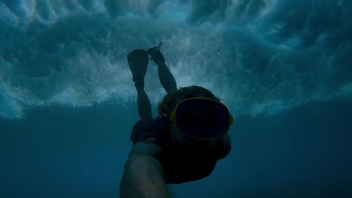 Young Man Snorkeling Underwater in Blue Ocean with Bubbles and Sunlight Rays