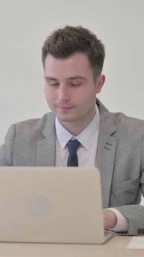 Young Businessman Gives Thumbs Up While Working on Laptop